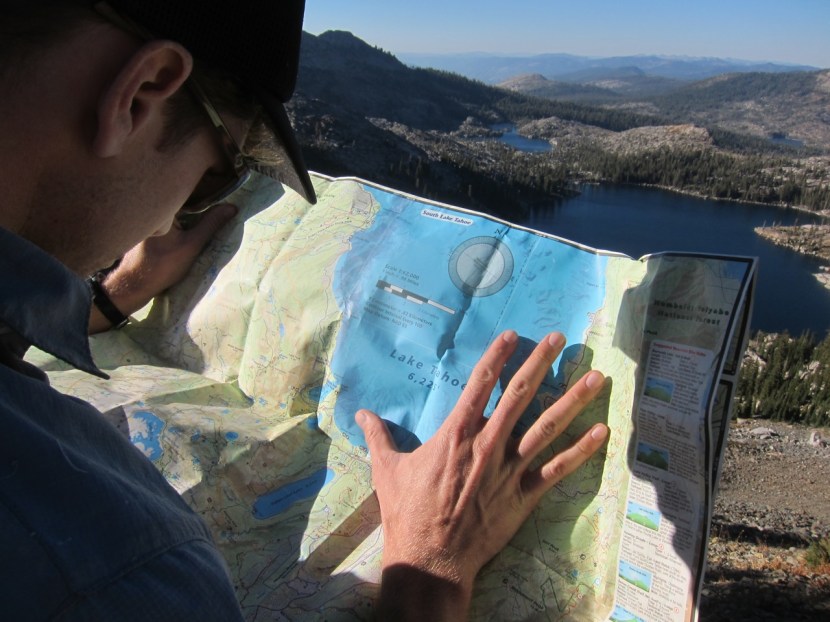 Kyle holding down the map in a slight breeze with Dicks Lake and Fontanillis Lake in the foreground.